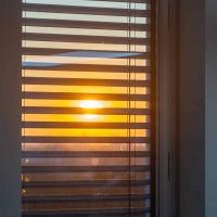 Sun seen through a window with external venetian blinds