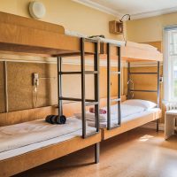 Cosy and quiet room with bunk beds and walls covered with warm colours and ecological environment and recycled materials. Family room. Shared hostel room. Nordic atmosphere and decoration.